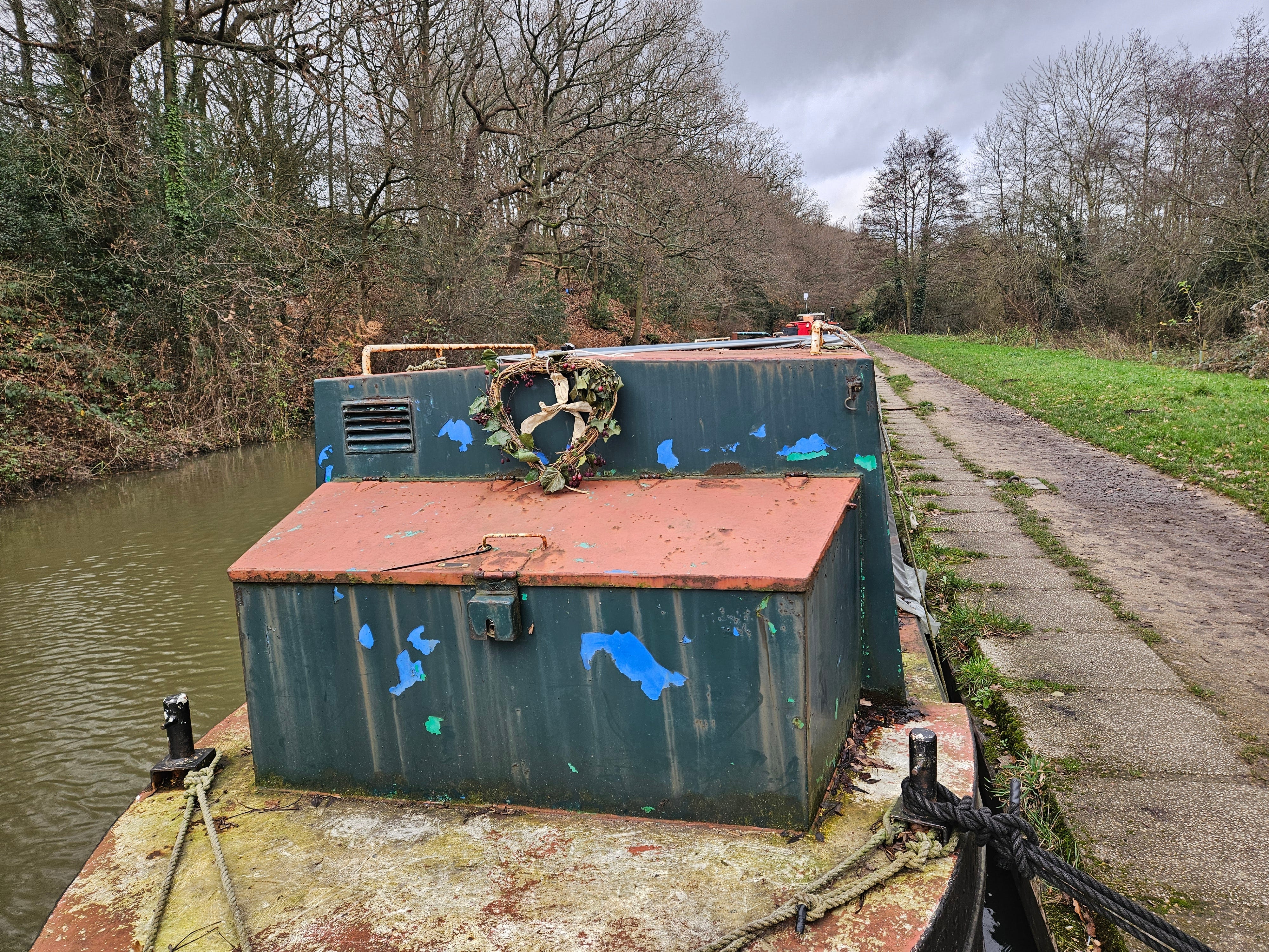 An image of the front of a narrowboat which carries a heart shaped wreath on the bow