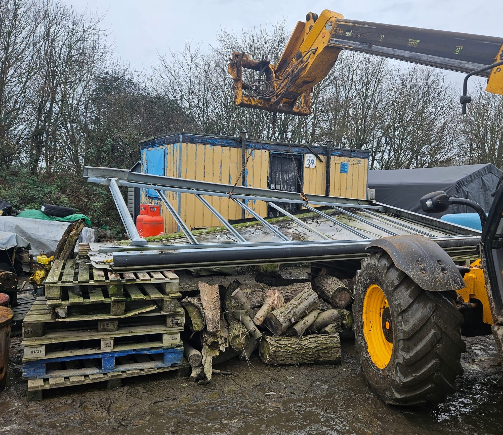 A section of box-section steel roof is lifted on chains using a telescopic fork lift truck